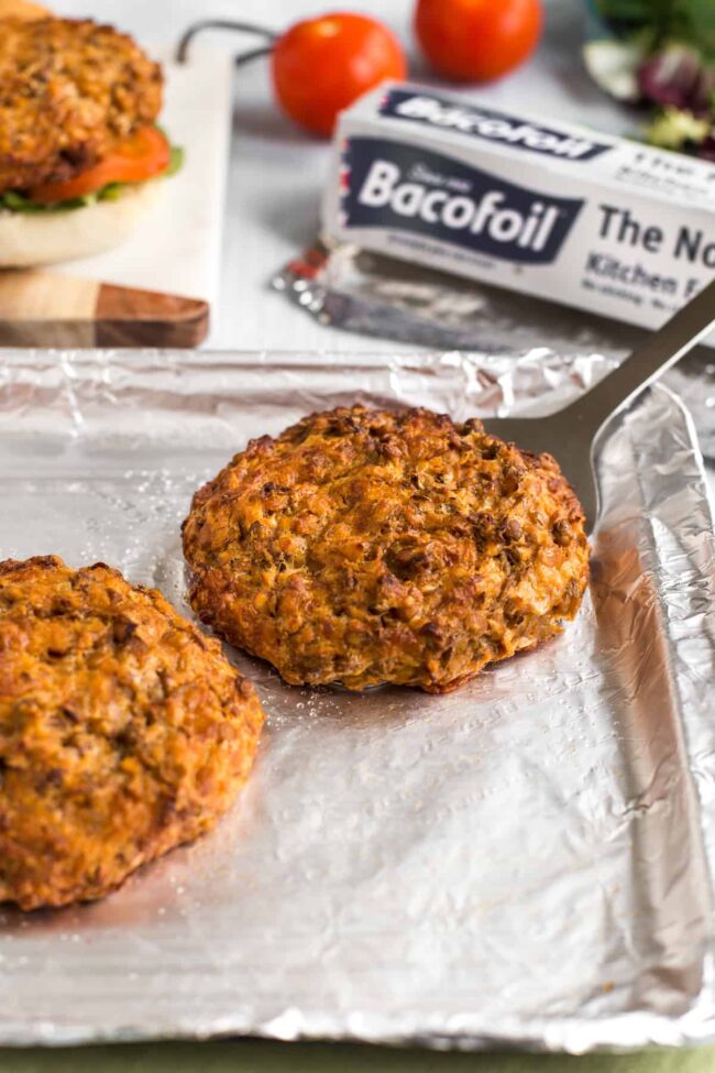 Burger di lenticchie su una teglia foderata di alluminio.