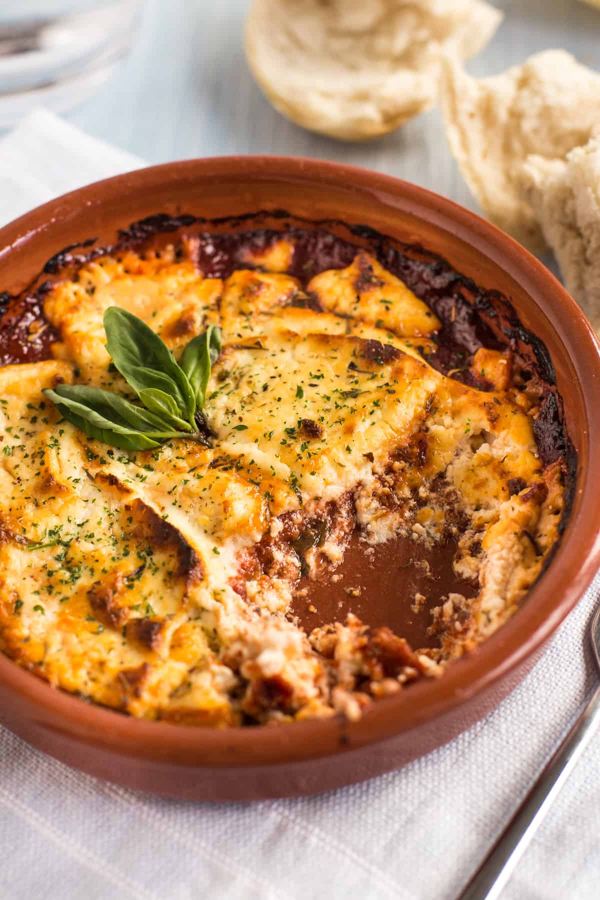 Baked goat's cheese in a dish with tomato sauce, with a scoop removed