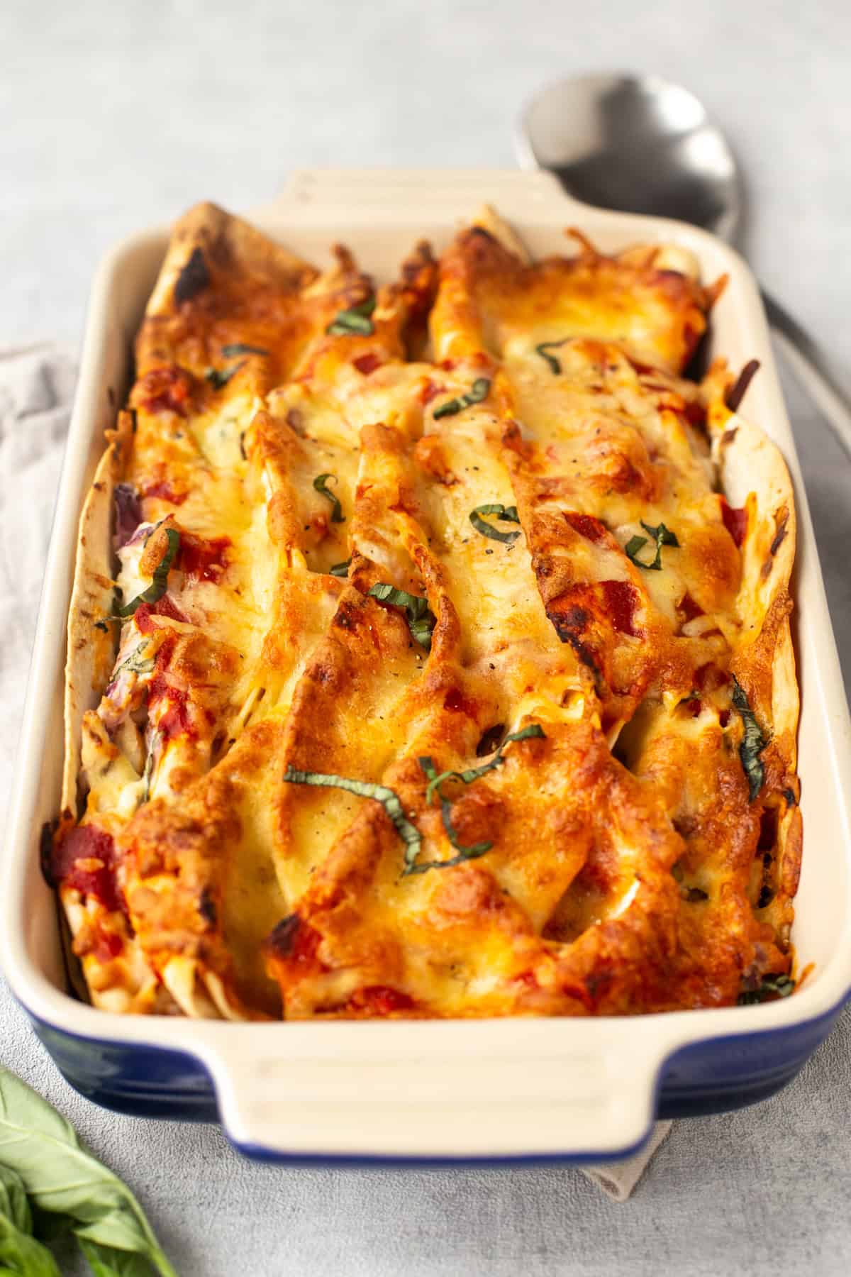 A baking dish with creamy zigzag tortilla bake topped with cheese.