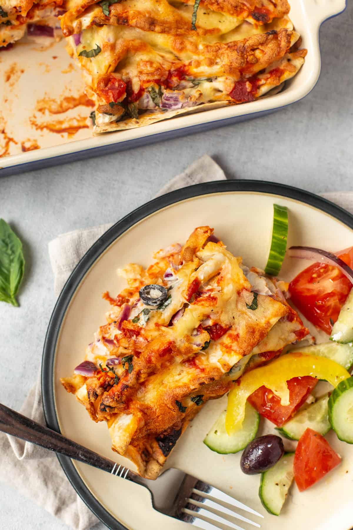 A portion of creamy zigzag tortilla bake on a plate with salad.