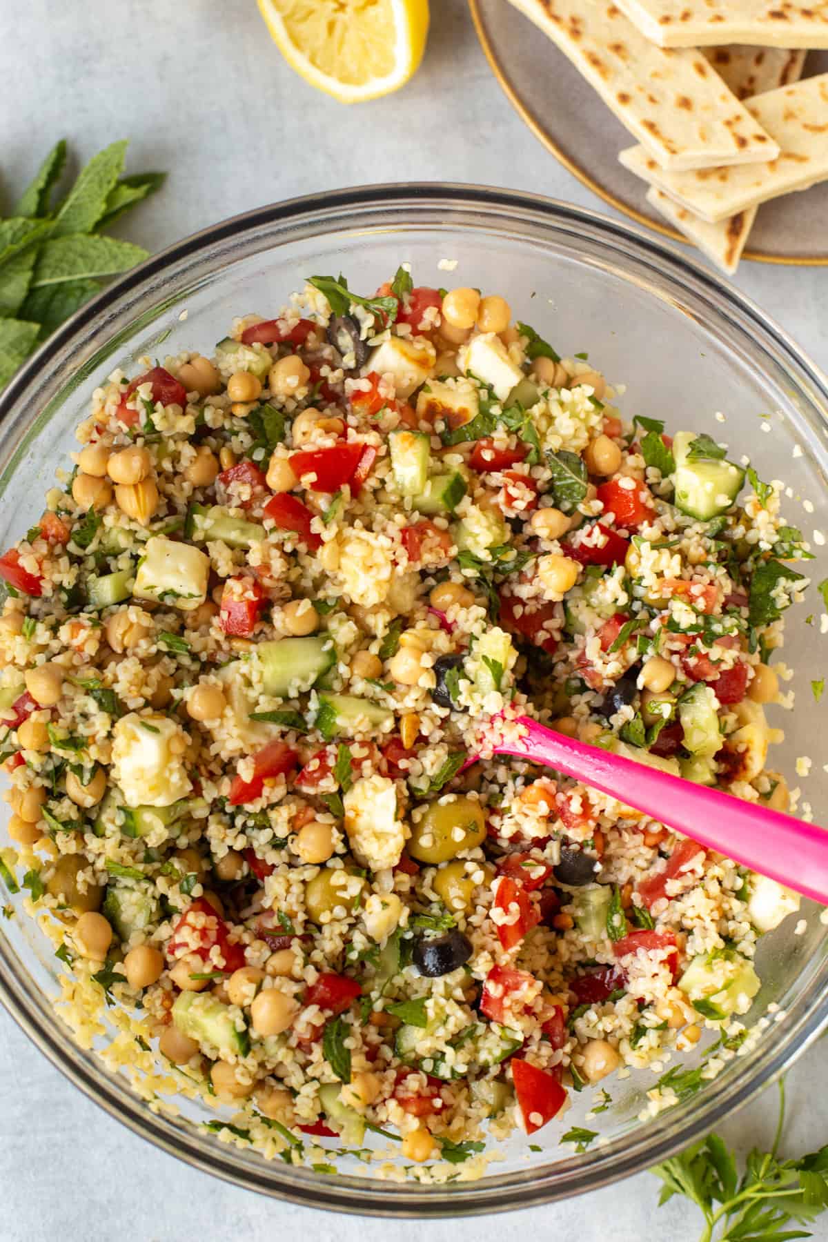 A mixing bowl full of tabbouleh salad with tomatoes and halloumi cheese.