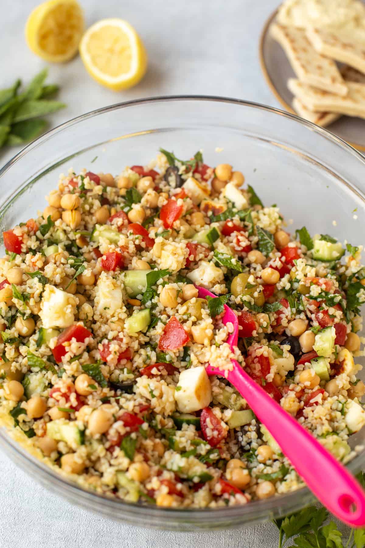 Tabbouleh salad in a bowl with extra cucumber and halloumi cheese.