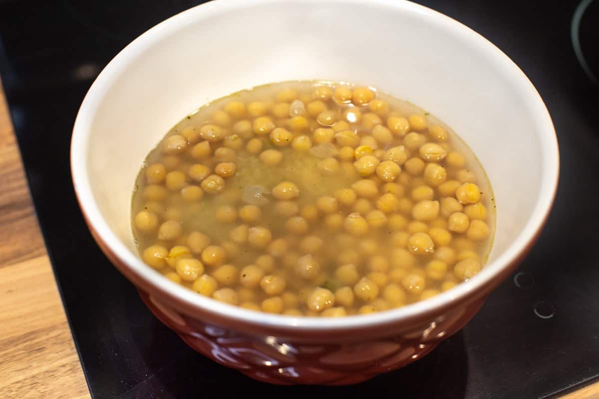 Chickpeas and bulgur wheat soaking in stock in a bowl.