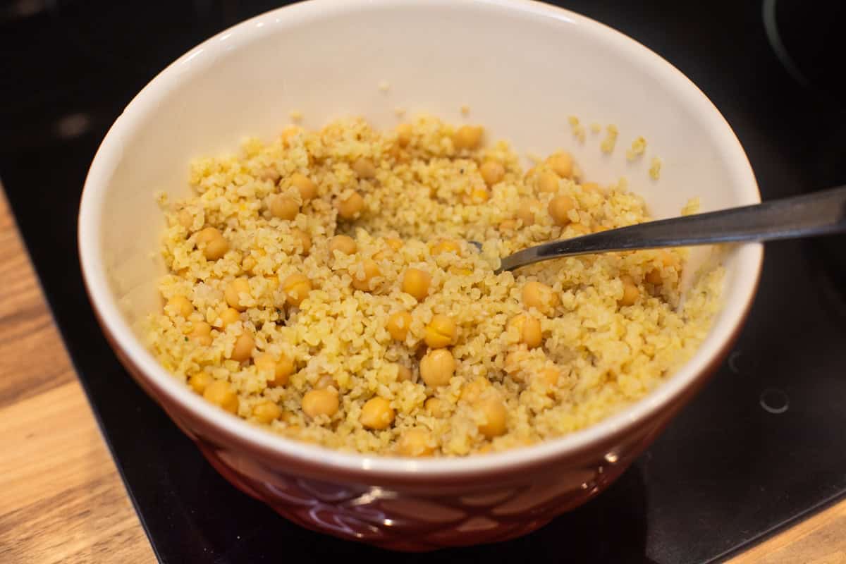 Cooked bulgur wheat and chickpeas in a mixing bowl.