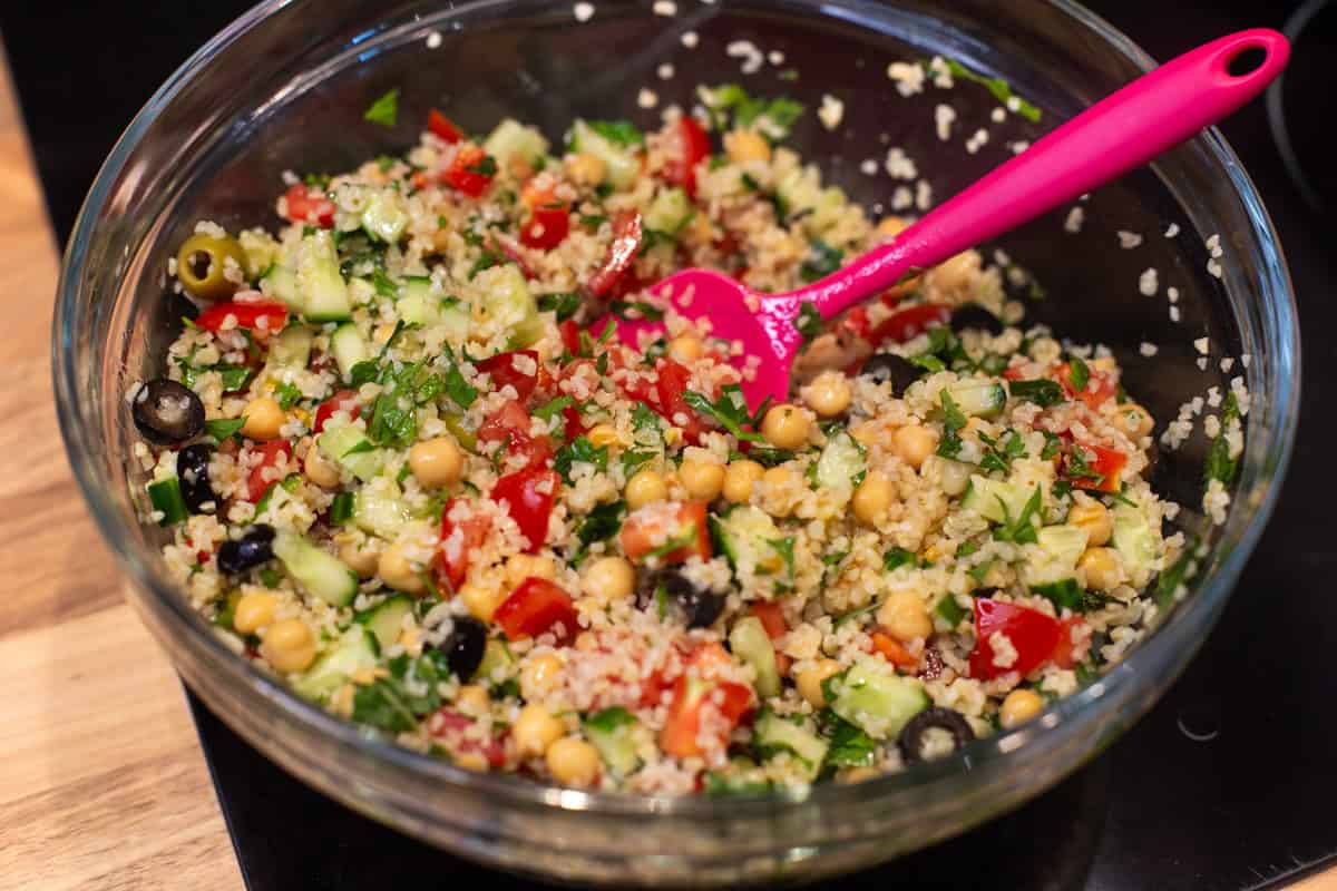 A simple tabbouleh salad with chickpeas and olives in a bowl.