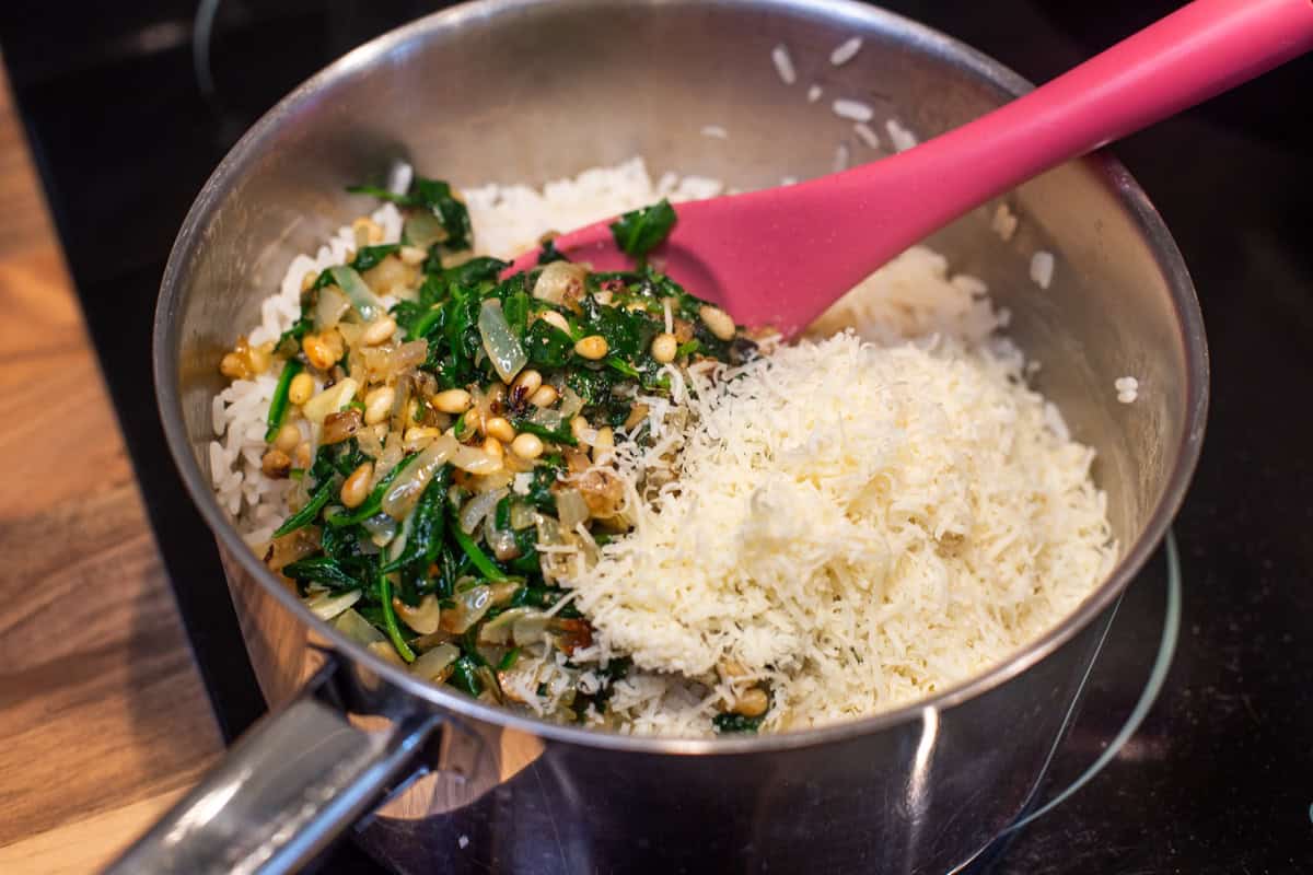 Cooked rice in a saucepan with garlic spinach and parmesan.