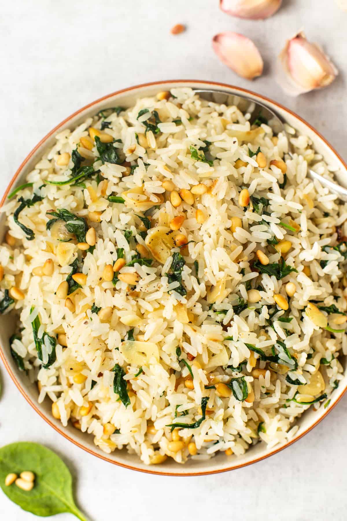 Garlicky rice in a bowl with spinach and pine nuts.