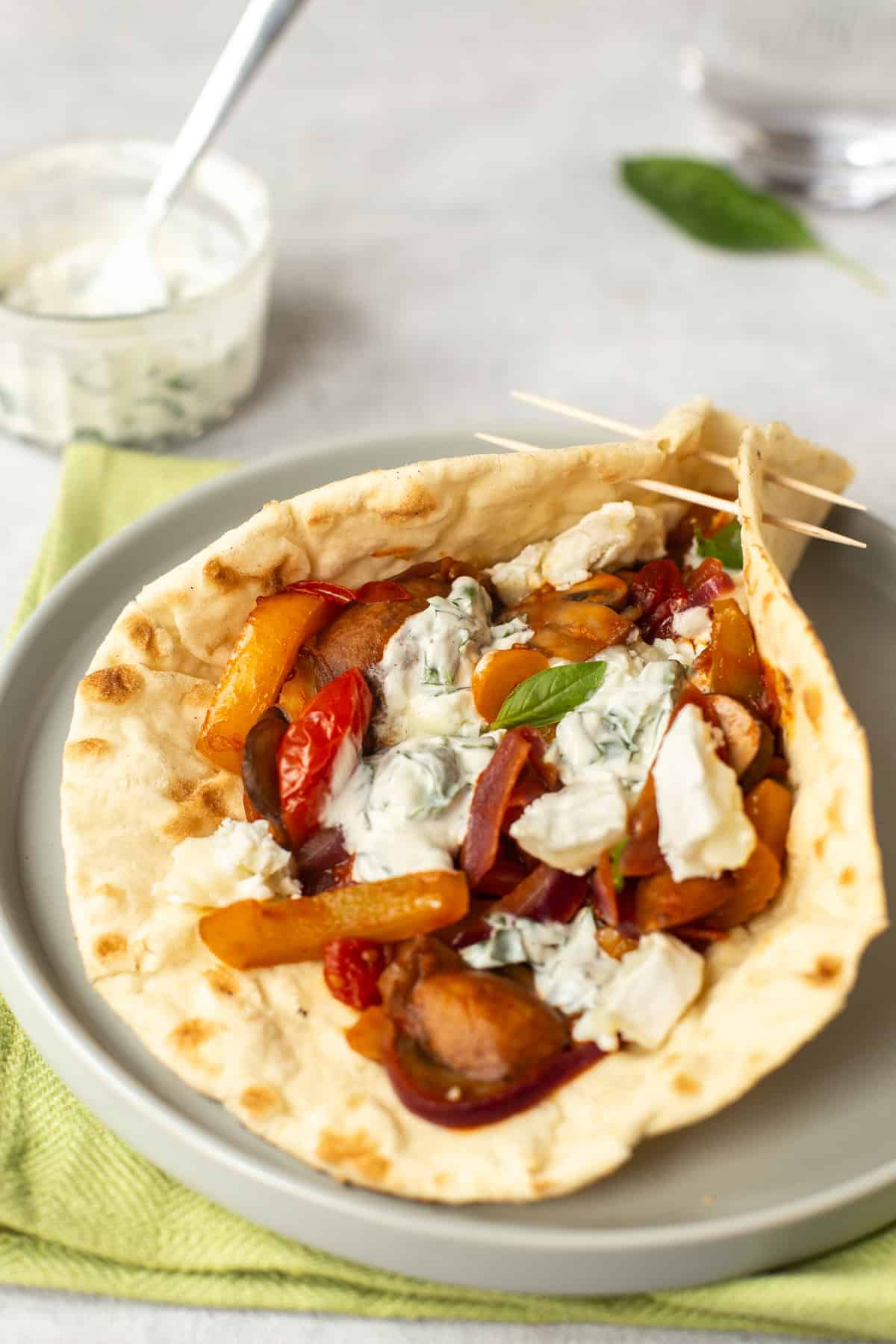 A flatbread partially wrapped around Mediterranean vegetables and goat cheese.