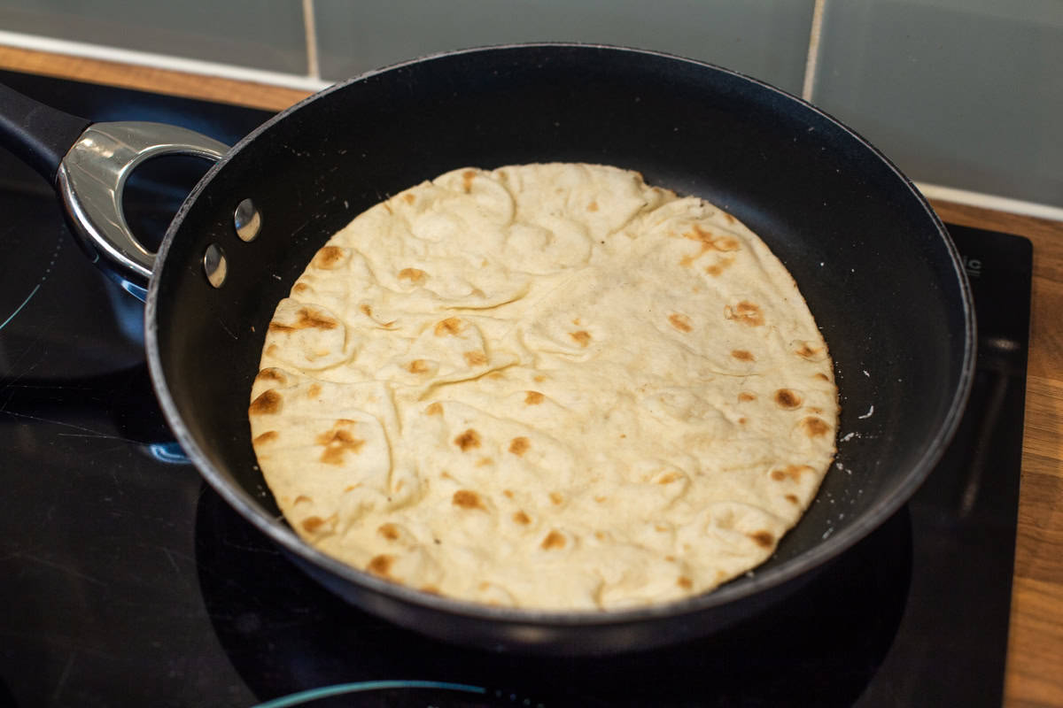 A chapatti warming through in a frying pan.