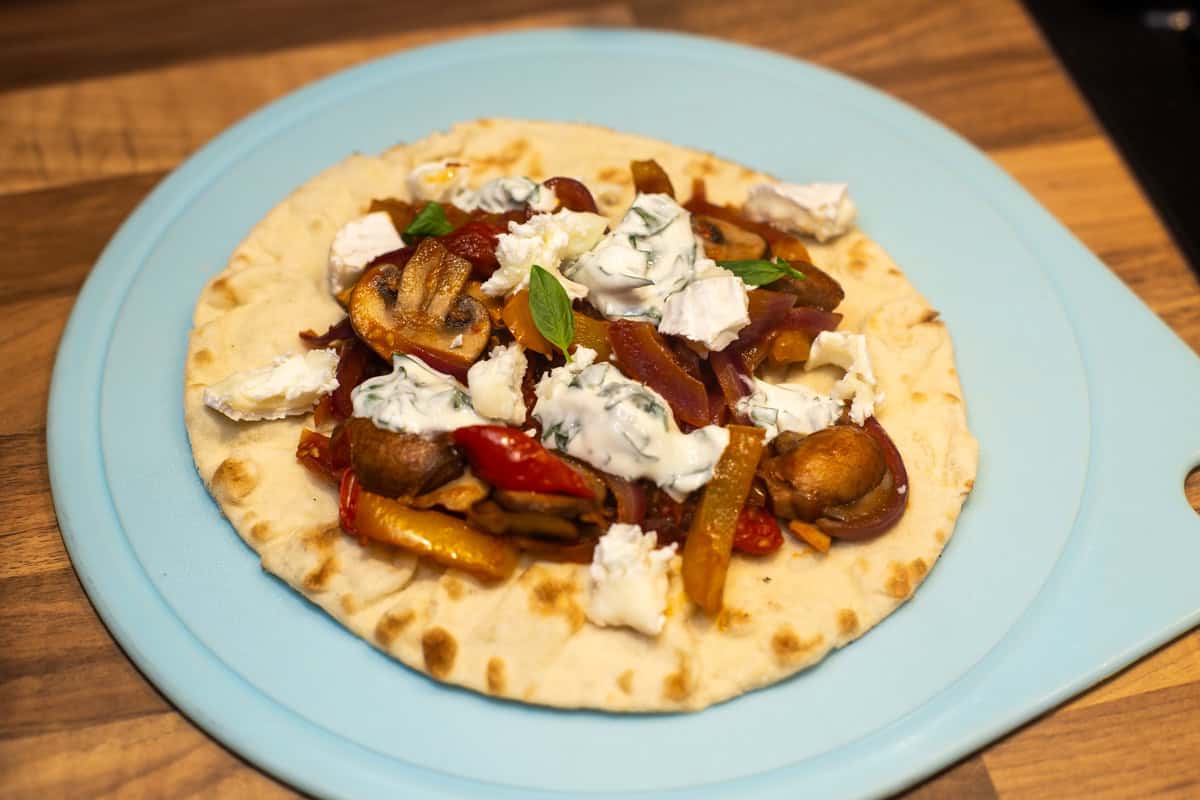 A flatbread topped with vegetables and sour cream.