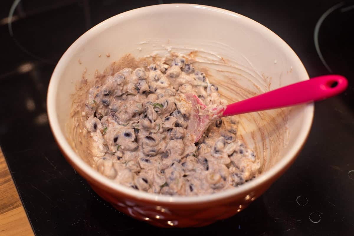 Creamy ricotta and black bean mixture combined in a mixing bowl.