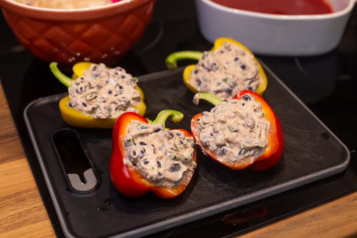 Peppers stuffed with ricotta and black beans on a board.