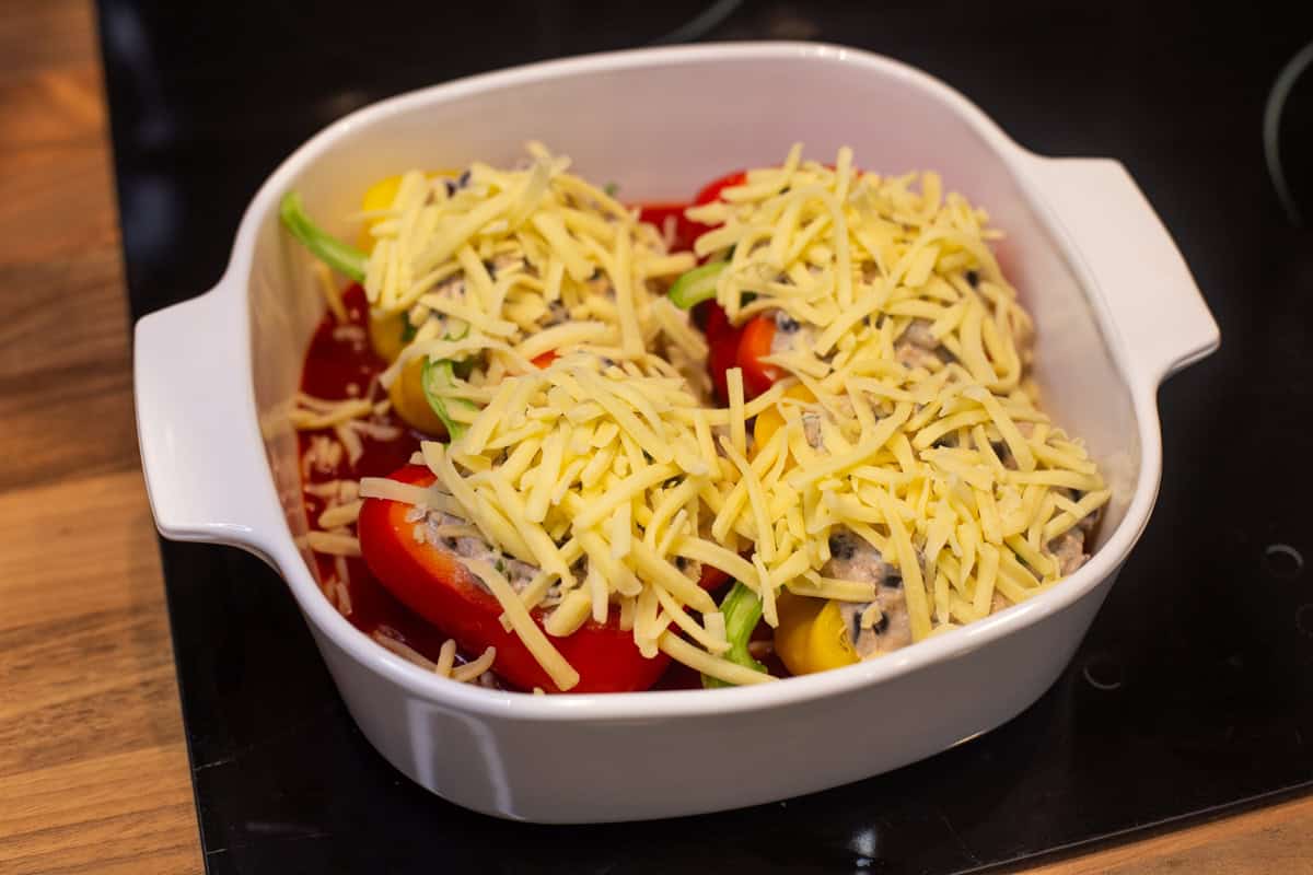 Uncooked cheesy stuffed peppers in a baking dish.