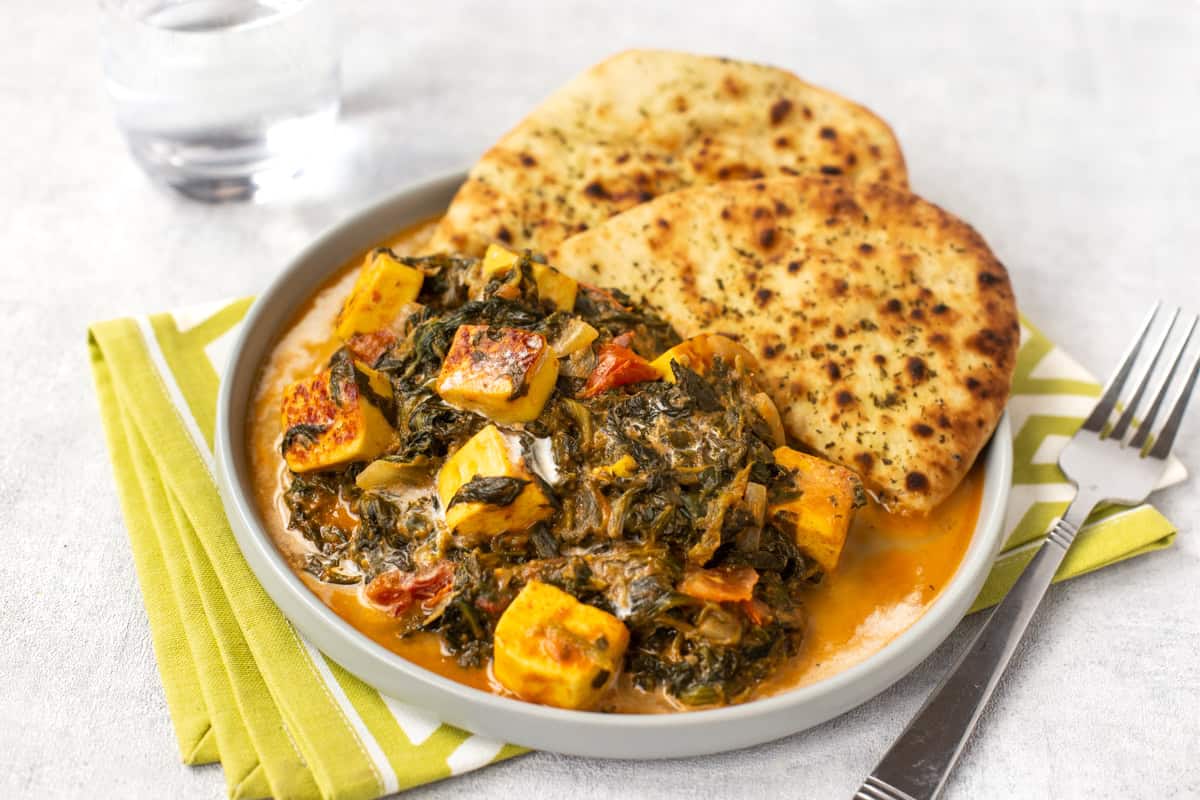 A plateful of creamy saag paneer (spinach curry with paneer cheese) and naan bread.