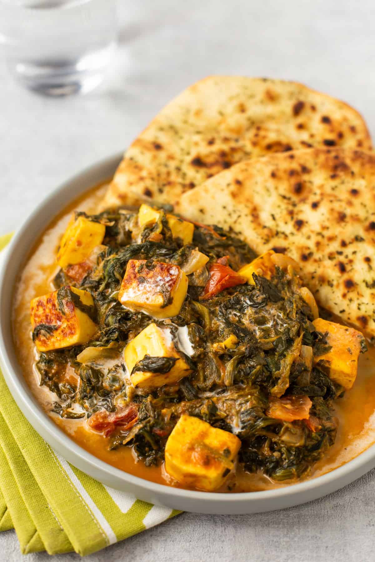 A portion of creamy saag paneer with naan bread on a plate.