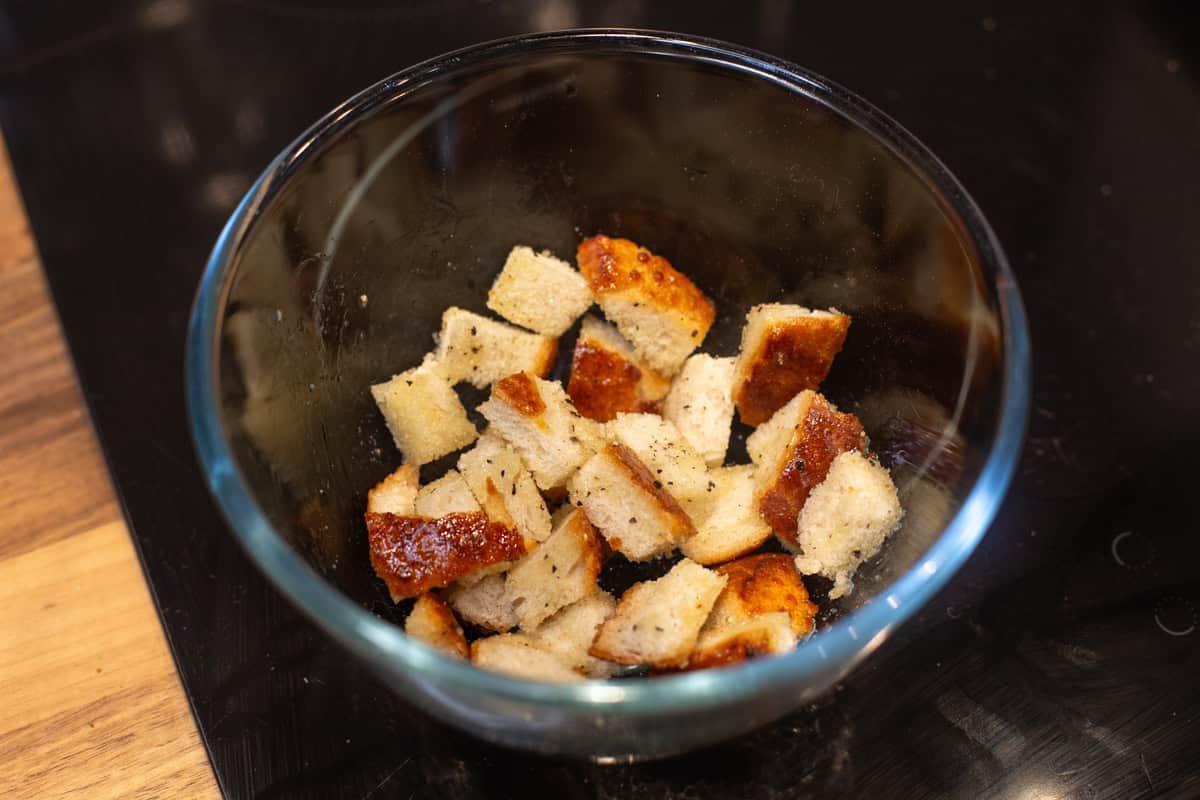 Cubes of crusty bread with olive oil and pepper in a bowl.