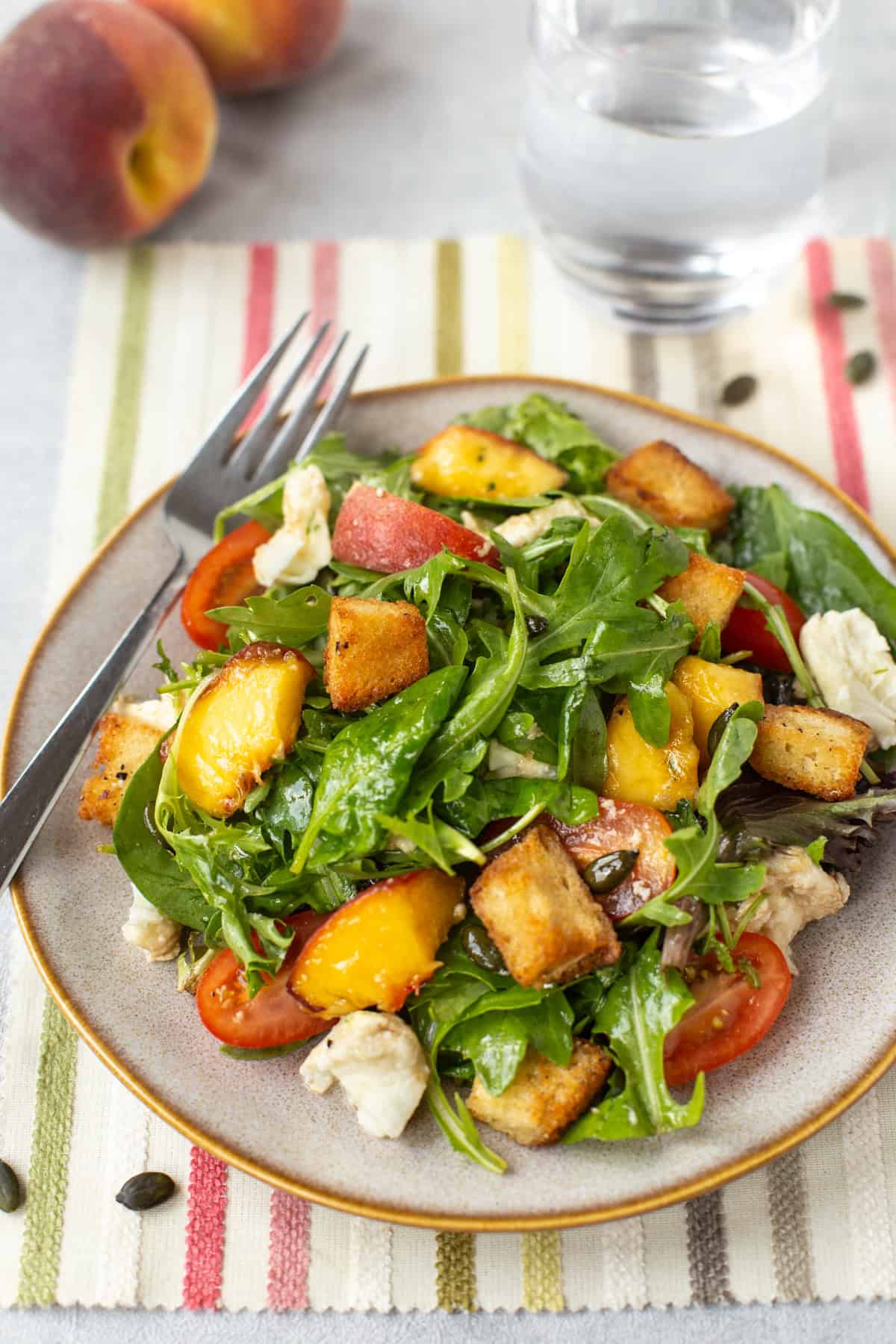 A plate with peach and mozzarella salad and homemade croutons.