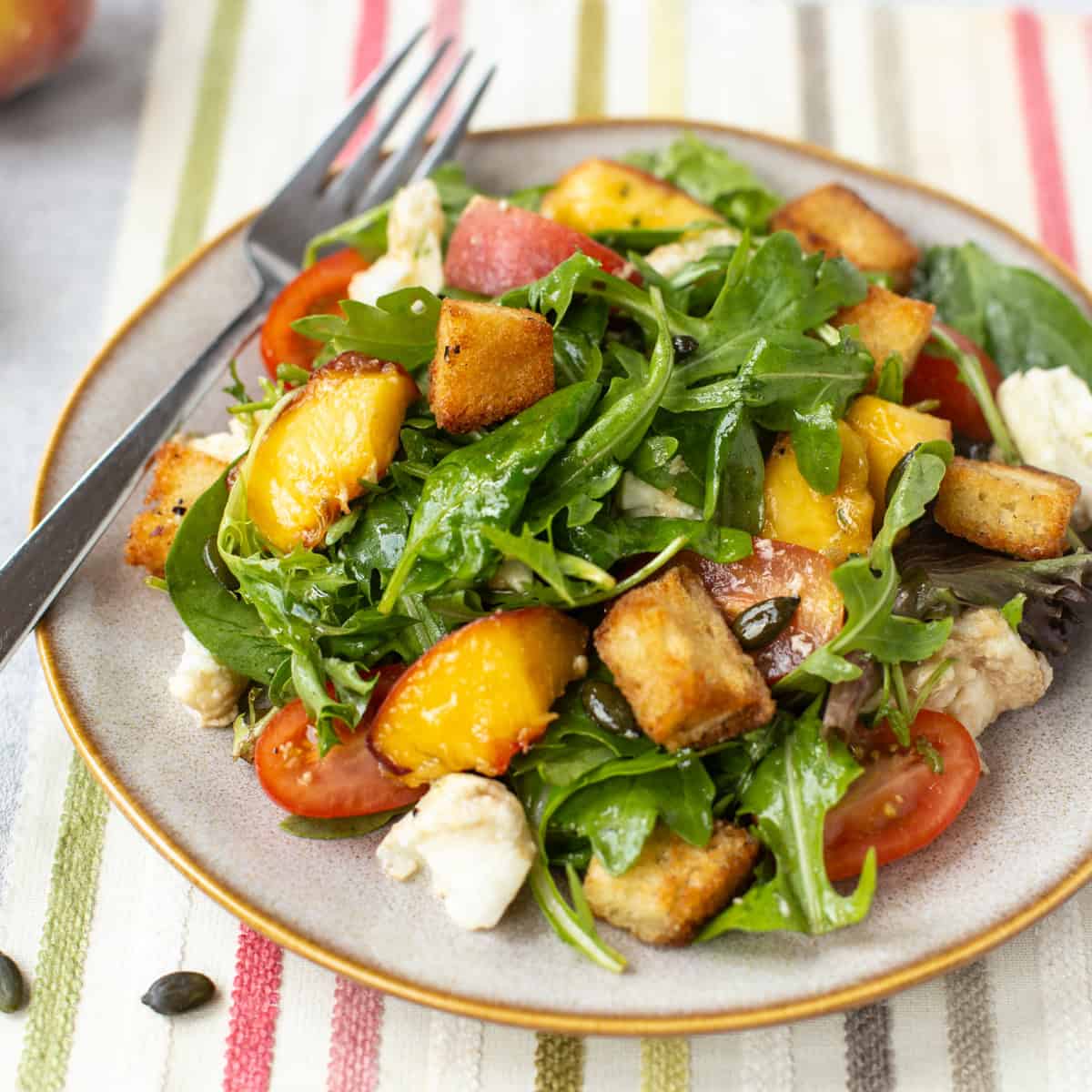 Peach and mozzarella salad with homemade croutons, tomatoes and pumpkin seeds.