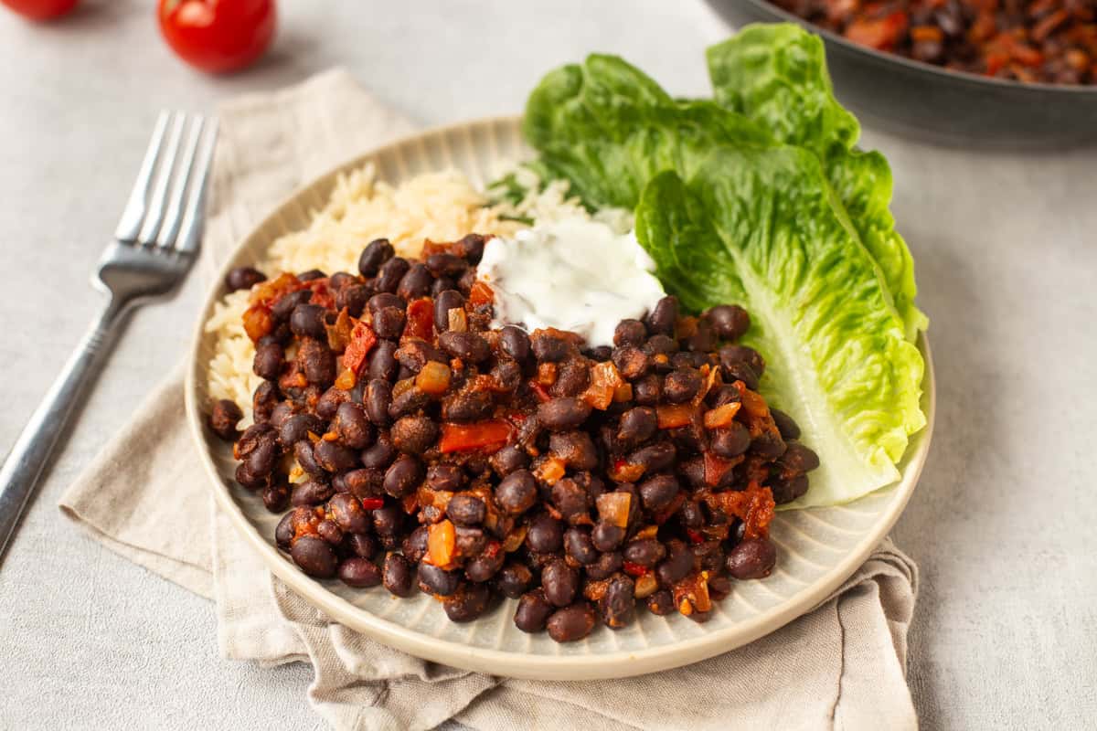 Vegan tomato and black bean stew with rice and lettuce.