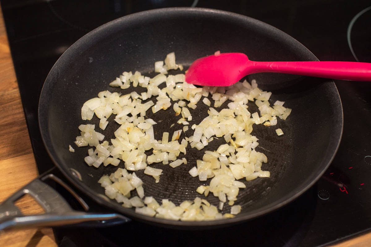 Finely diced onions cooking in a frying pan.