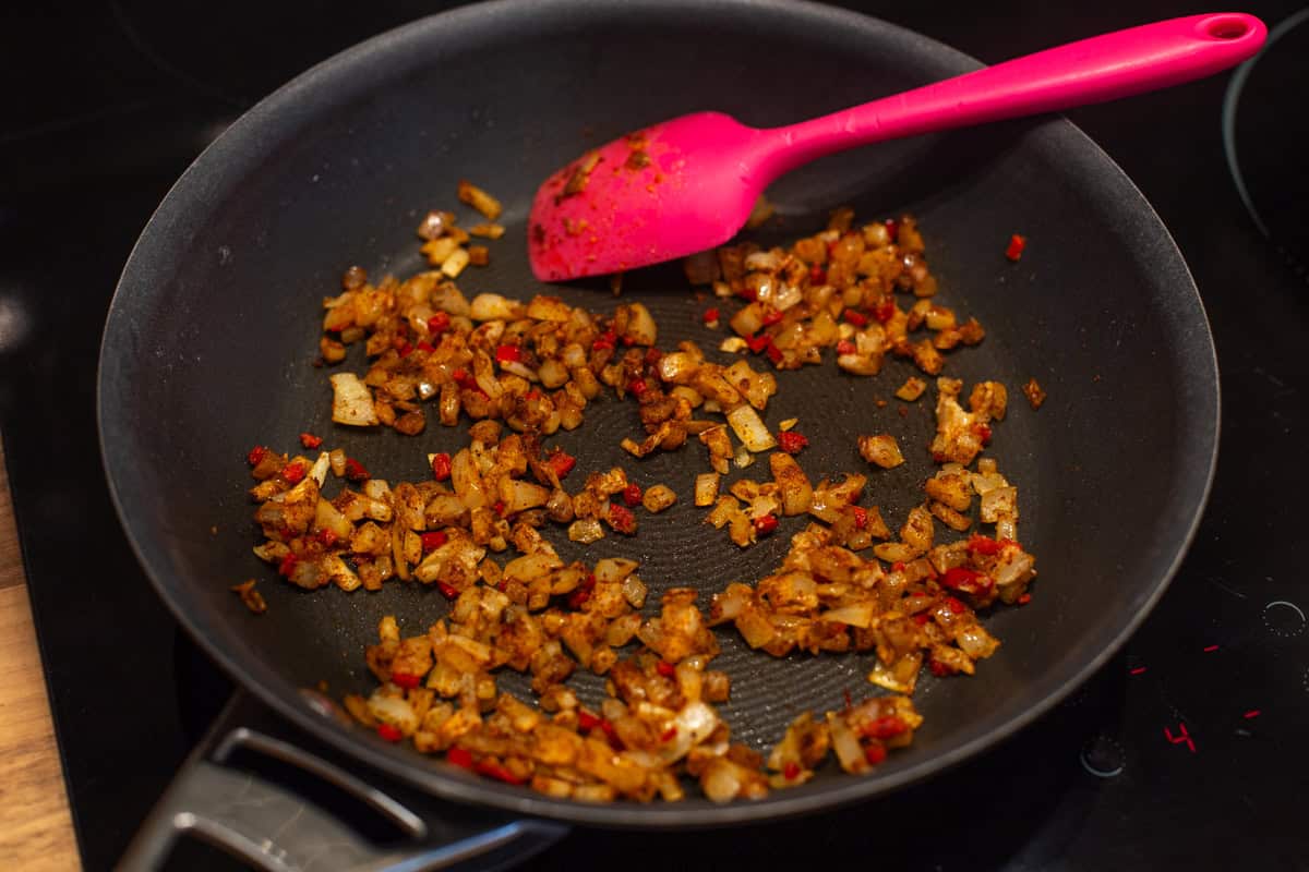 Spiced onions cooking in a frying pan.