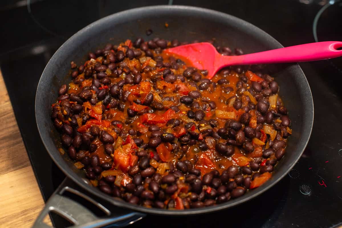 Rich tomato and black bean stew in a frying pan.