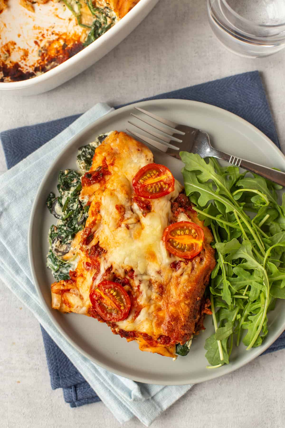 Overhead shot of creamy spinach enchiladas topped with cheese and tomatoes.