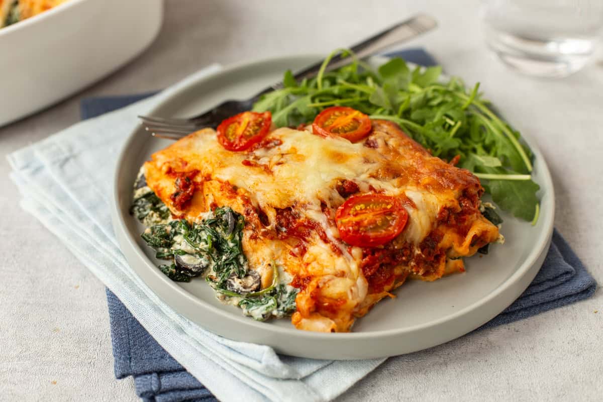 Creamy spinach and ricotta enchiladas on a plate with a cheesy topping.