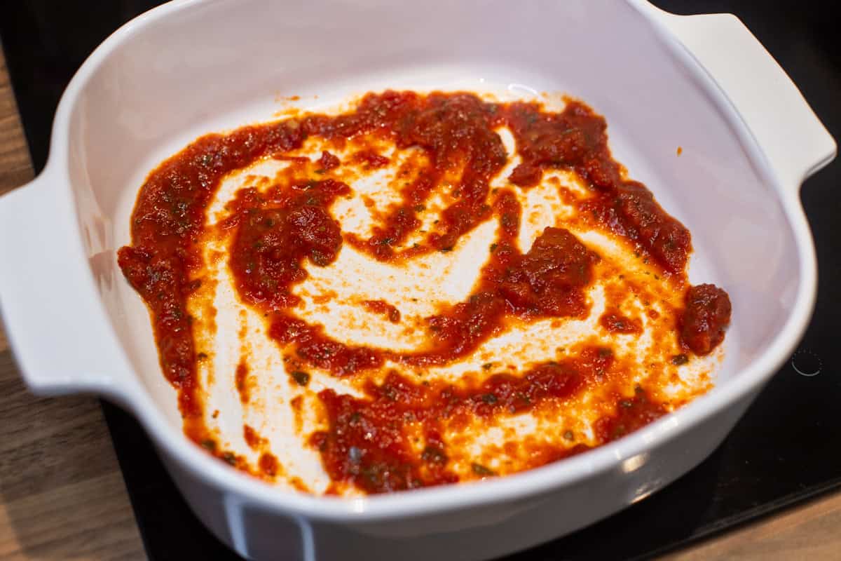 Tomato sauce spread around the base of a baking dish.