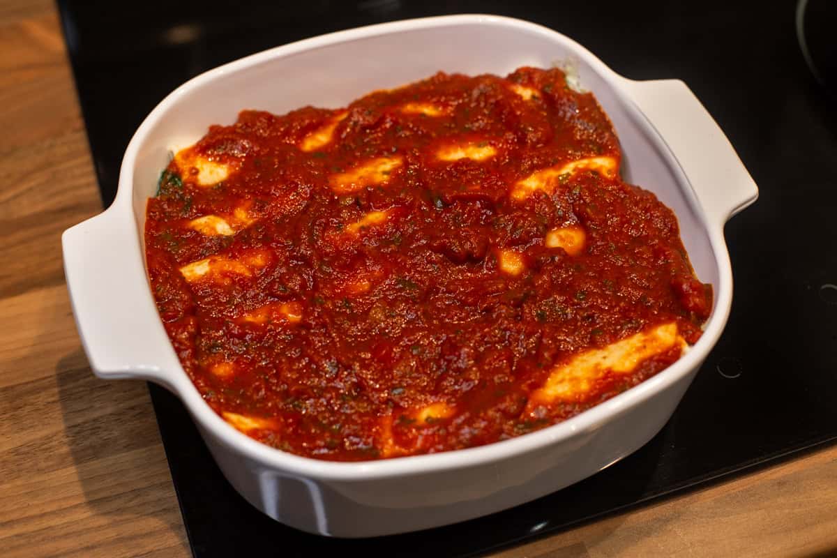 A dish of enchiladas smothered with tomato sauce.