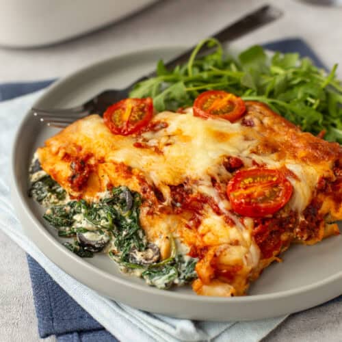 A portion of spinach and ricotta enchiladas on a plate with arugula.