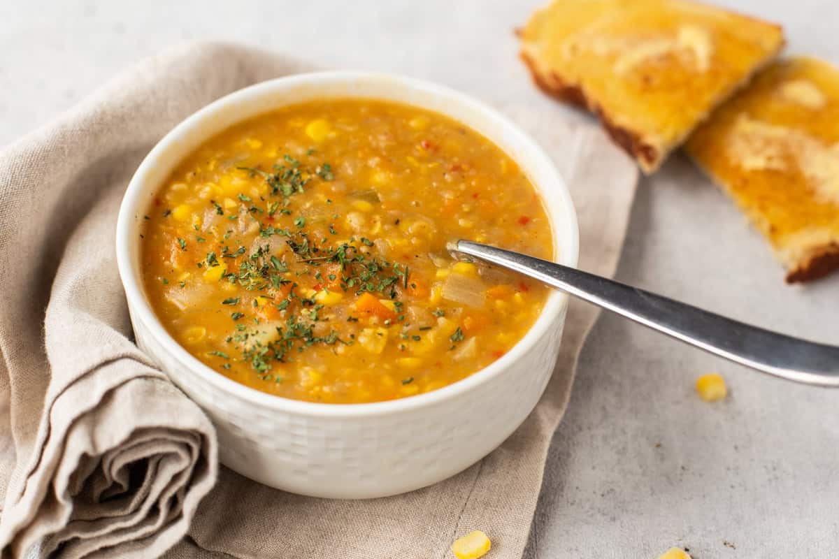 Coconut corn chowder in a bowl with buttered toast.