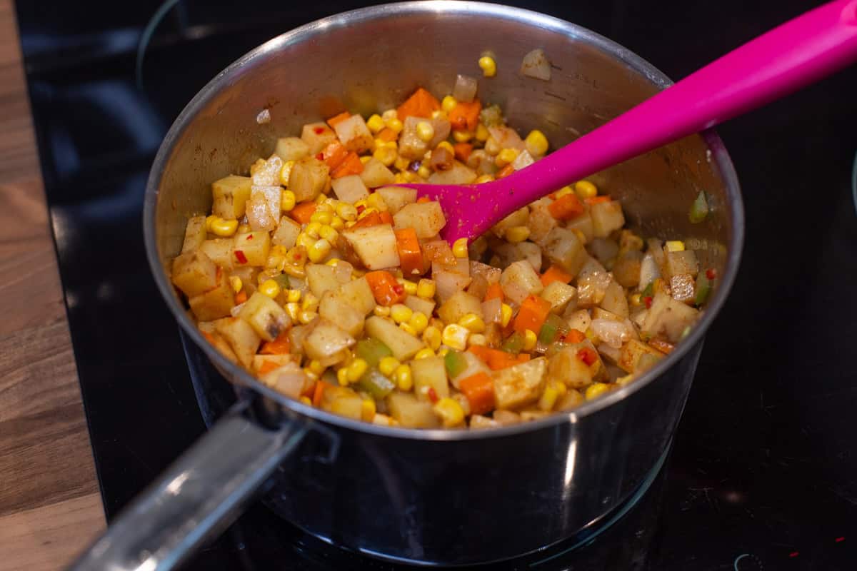 Sautéed vegetables and spices in a saucepan.