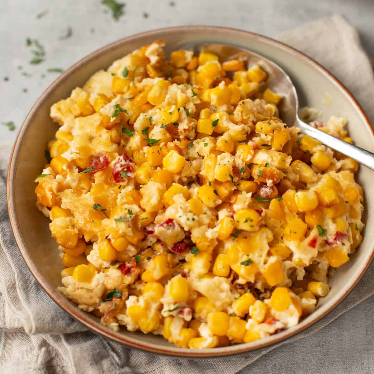 A bowl of slow cooker corn casserole with a spoon.