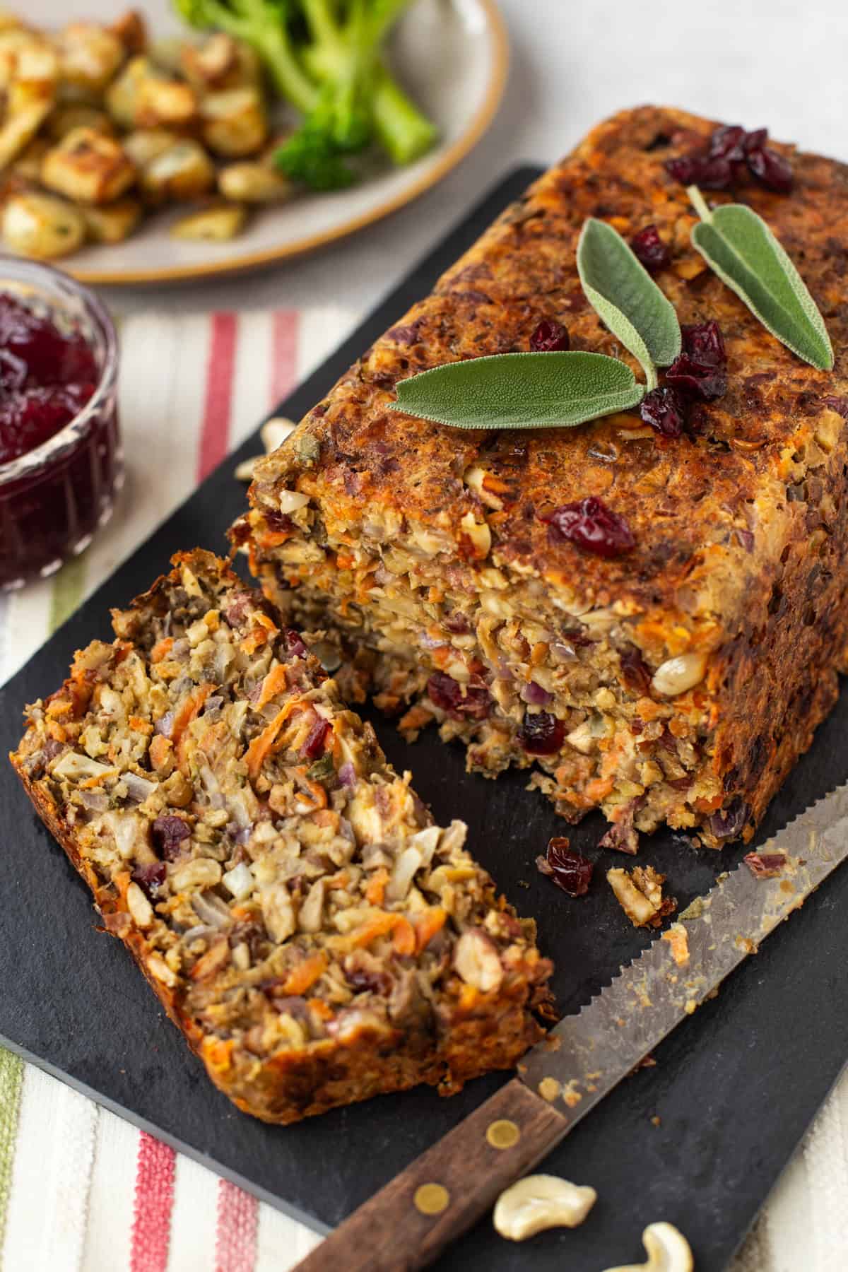 A vegetarian nut roast on a board with a slice cut off.