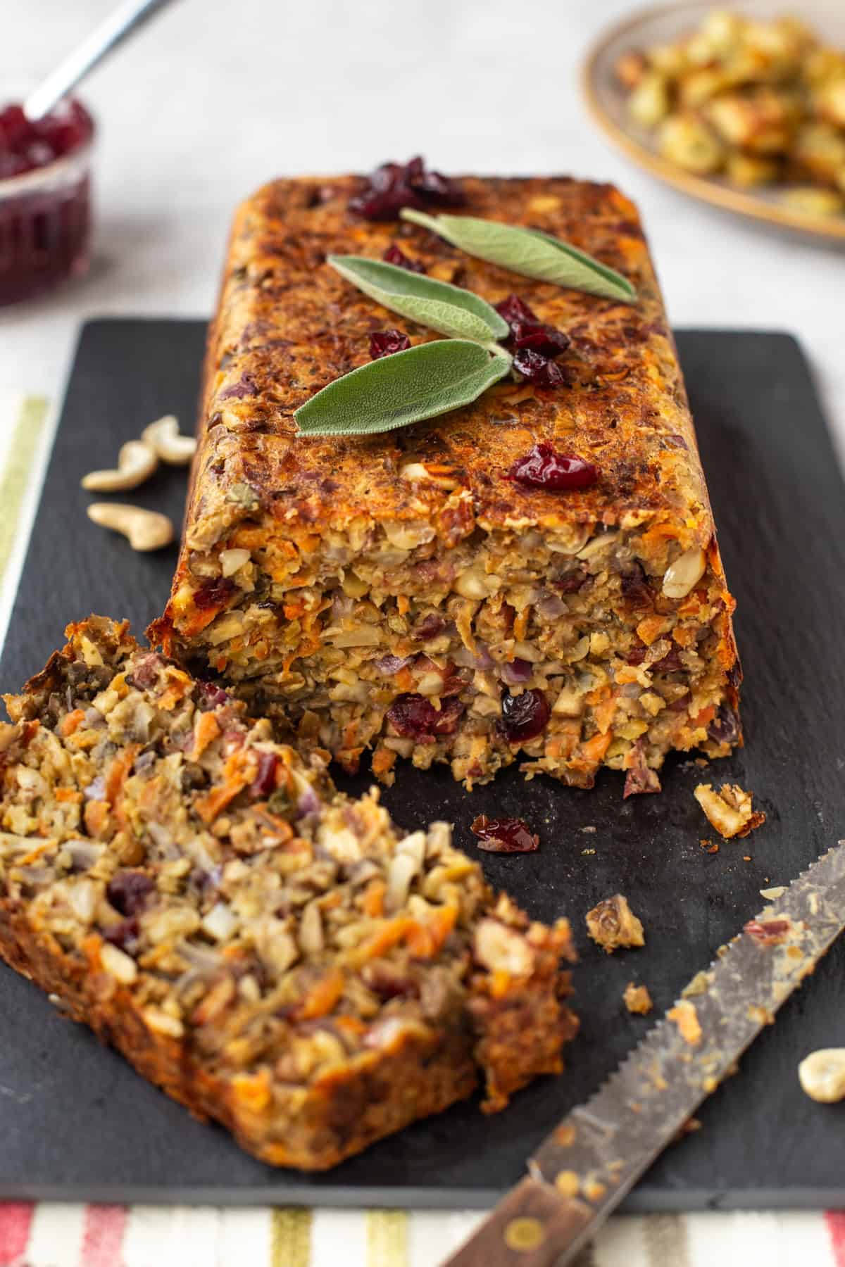 A vegetarian nut roast on a board with a slice cut off.