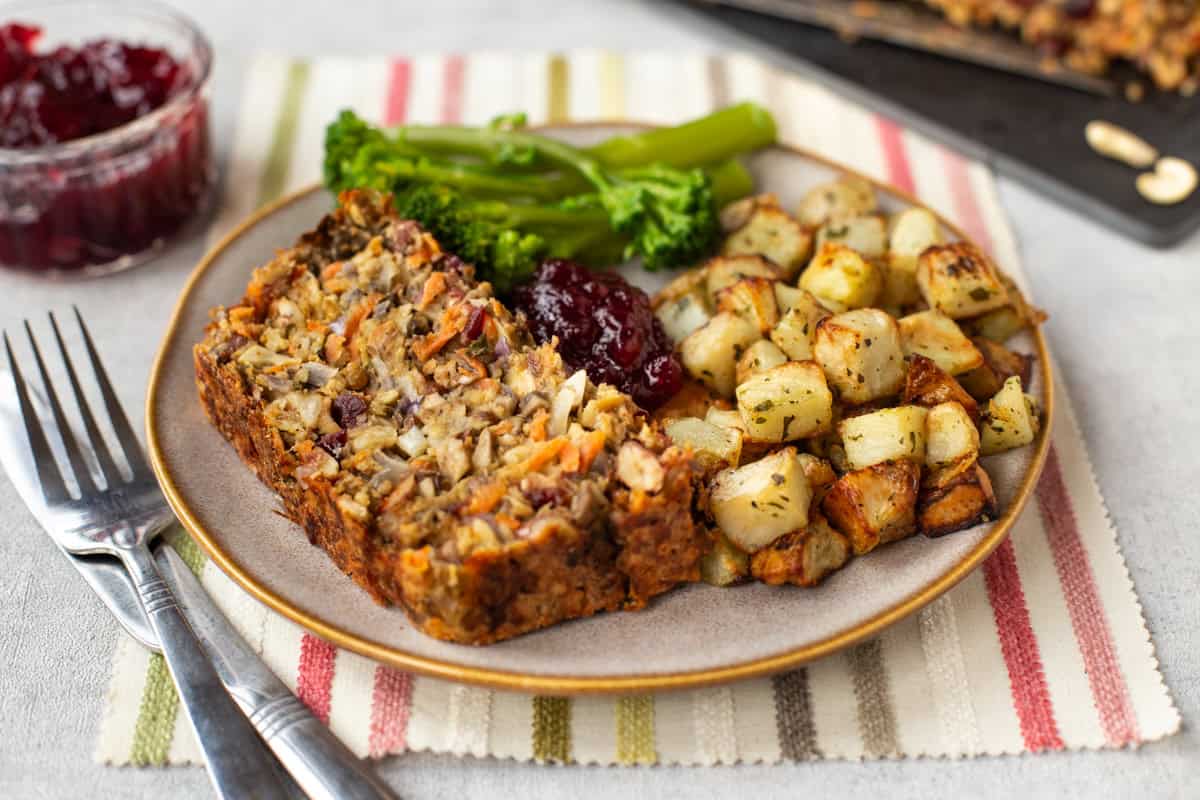 A slice of nut roast served with broccoli and potatoes.