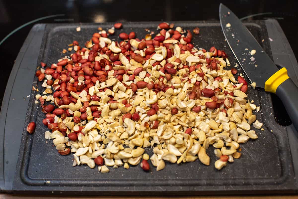 Chopped peanuts and cashew nuts on a cutting board.