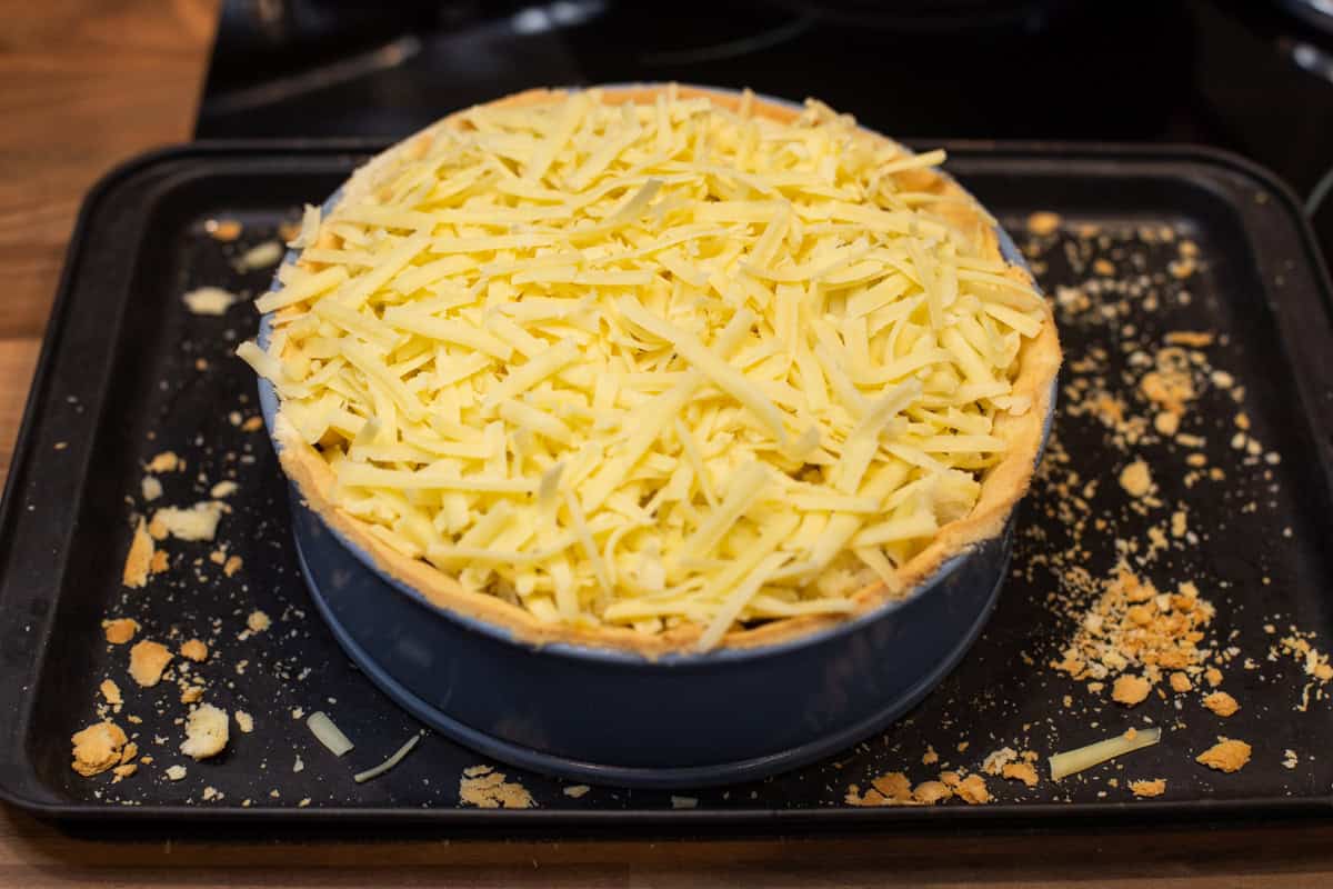 A pastry case topped with grated cheese.