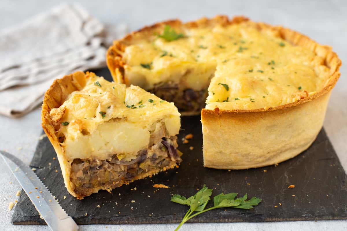 A cheesy potato and leek pie with a slice removed.