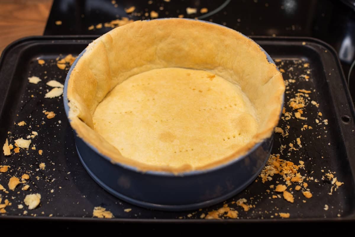 A cake tin lined with trimmed, cooked pastry.