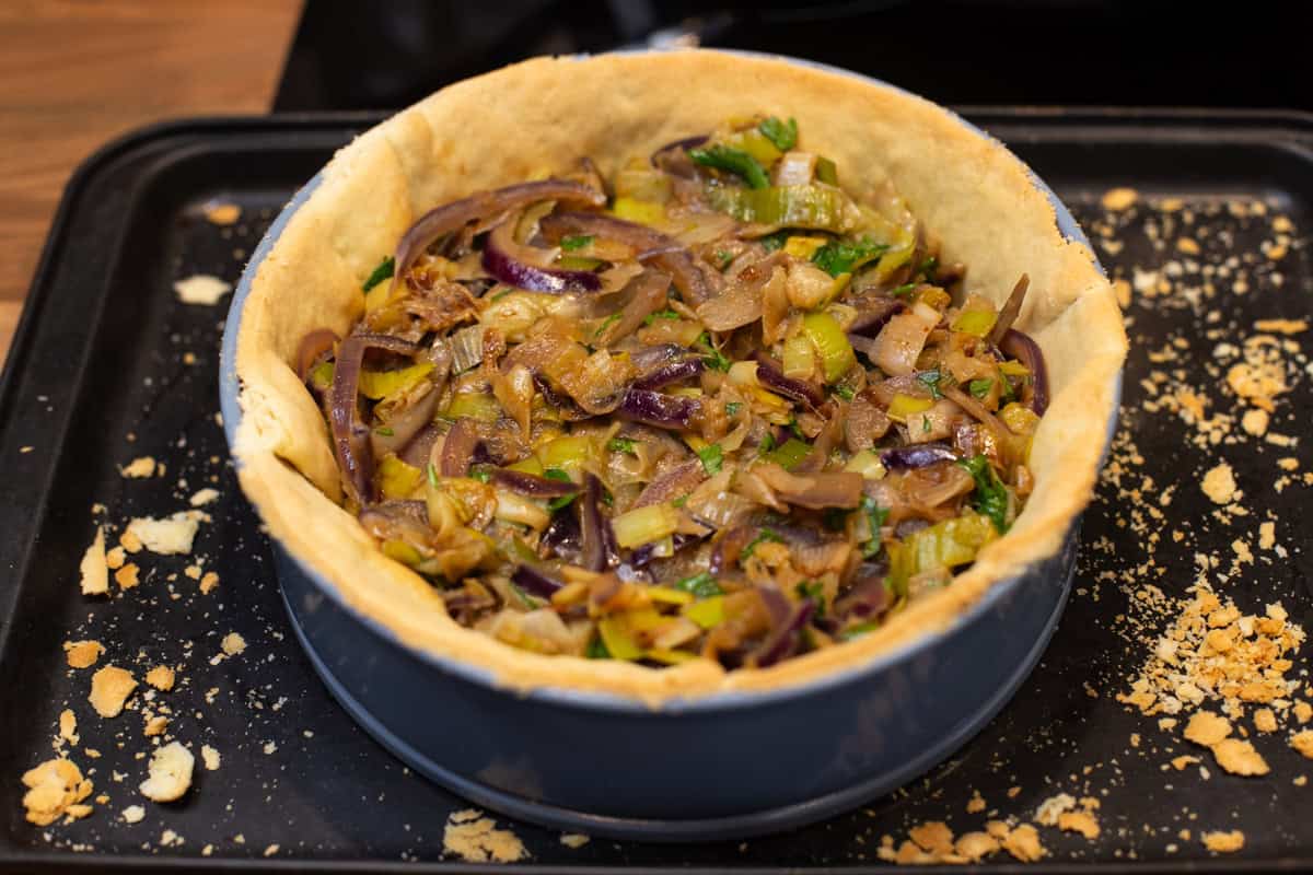 A pastry case filled with sautéed leeks and red onion.