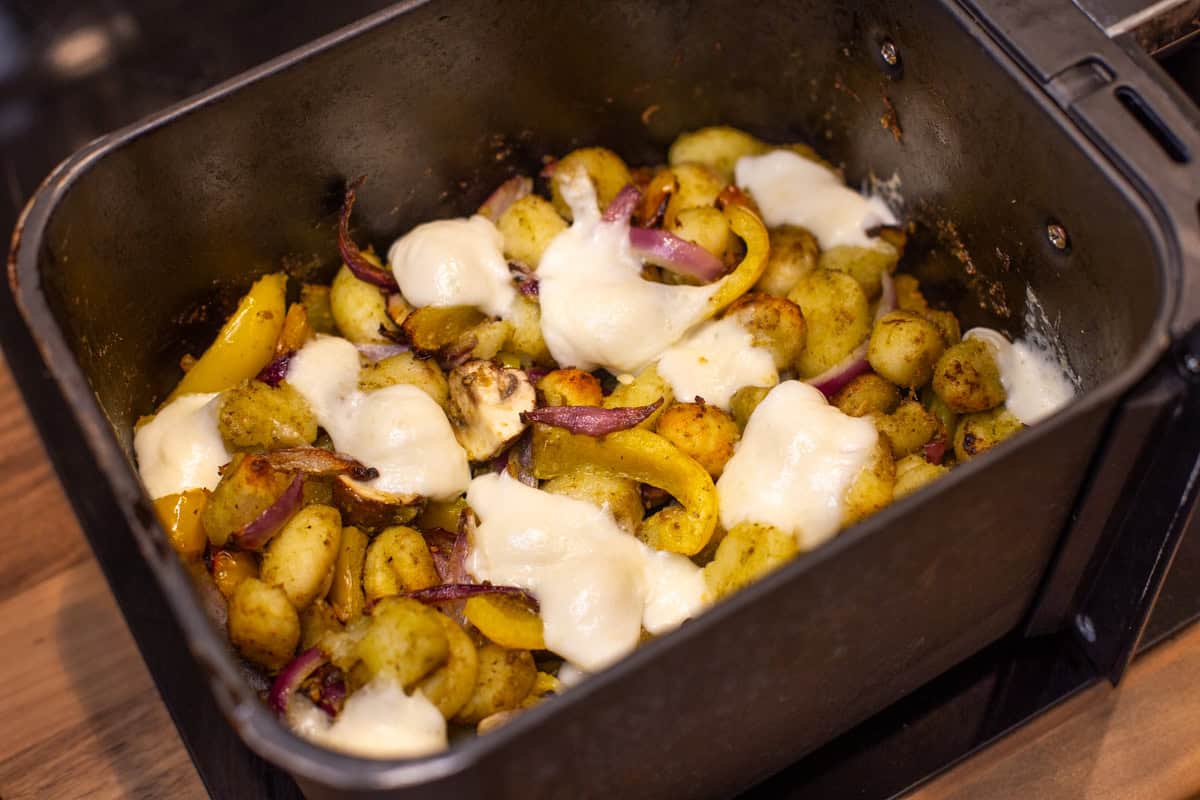 Air fryer gnocchi and vegetables topped with melted mozzarella.