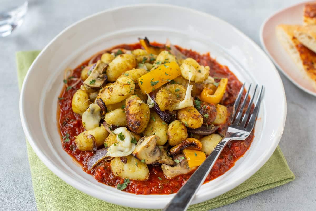 Air fried gnocchi and vegetables served on tomato sauce.