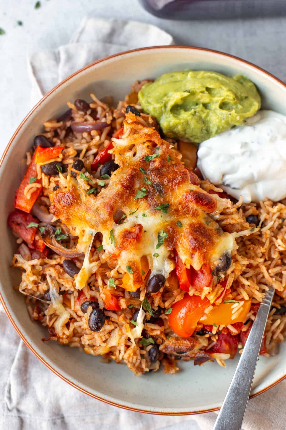 A bowl of baked fajita rice with a cheesy topping.