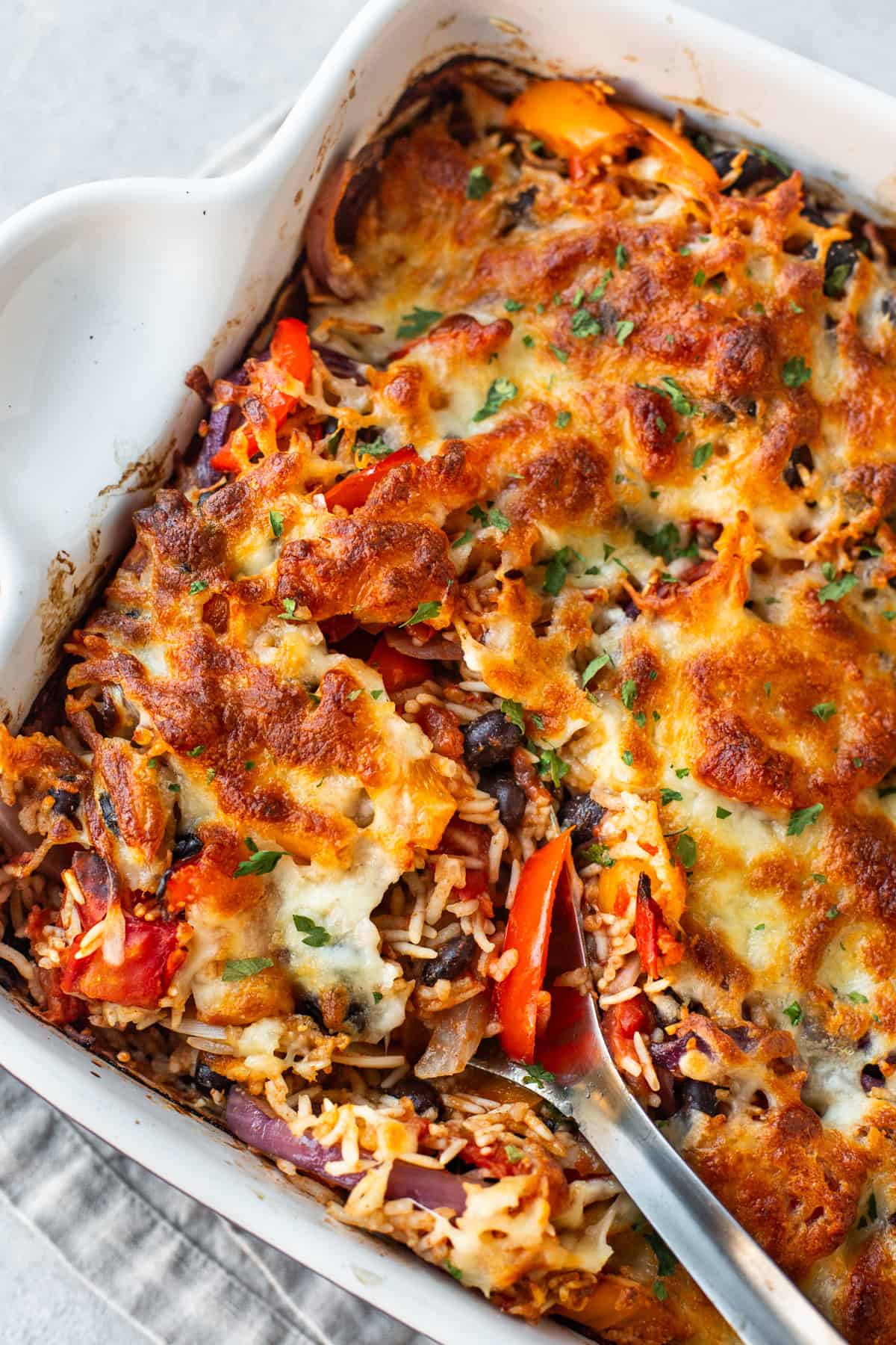 Cheesy fajita baked rice in a large baking dish with a spoon.