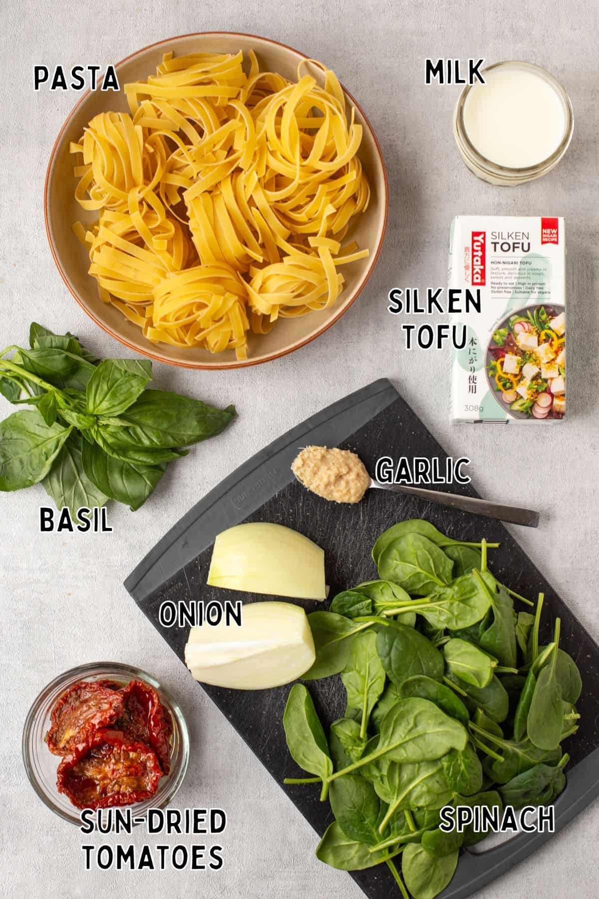 Ingredients for creamy tofu pasta laid out with text overlay.