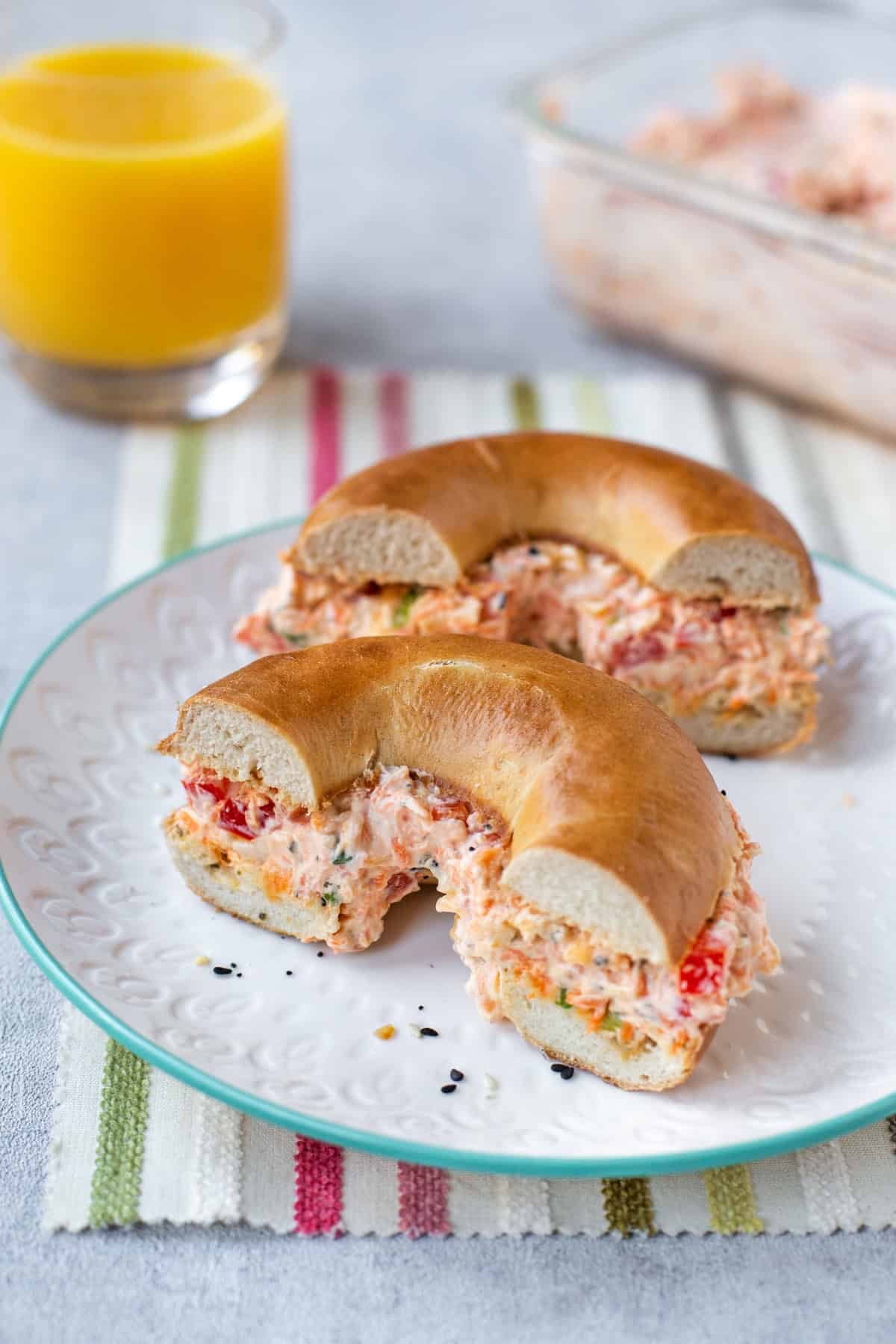 A halved bagel stuffed with vegetable cream cheese on a plate.