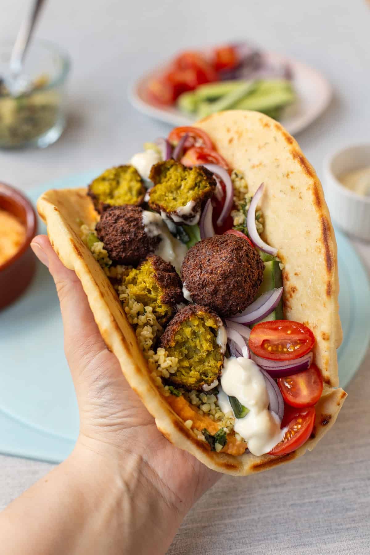 A hand holding an easy tabbouleh and falafel wrap.